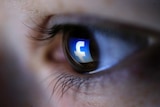 A Facebook logo is reflected in a person's eye