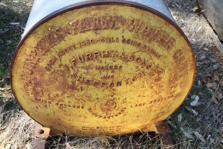 The end of an old Furphy water cart includes a stork figure.