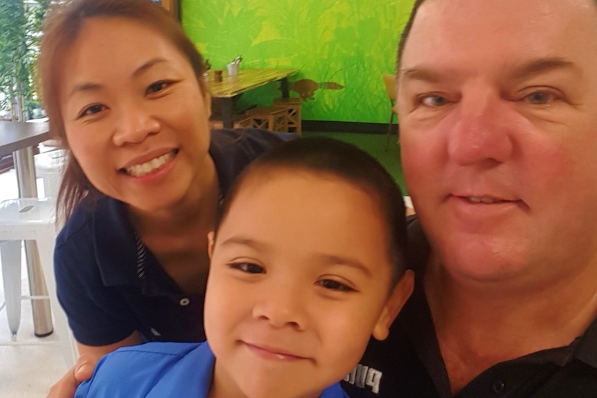 Oscar in his school uniform posing for a photo with his parents, Tim and Nui Gordon, at their family owned cafe