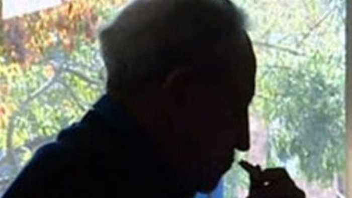 A silhouette of an older man sitting down looking thoughtful