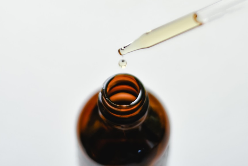 A liquid dropper is pulled out of a small brown glass bottle. 