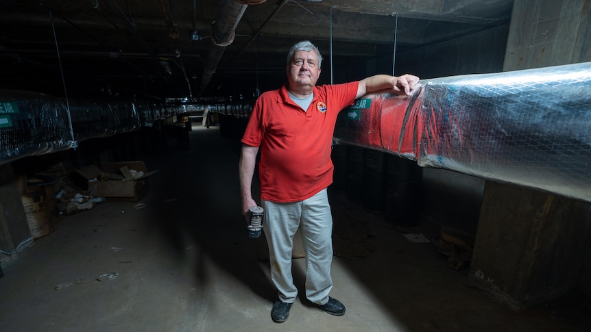 A man in a red polo shirt stands inside an underground bunker