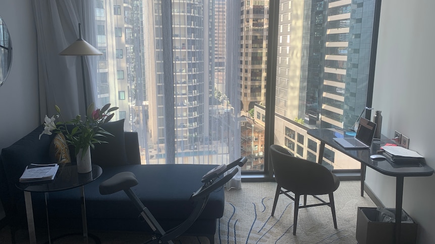 A large hotel room window overlooks the city