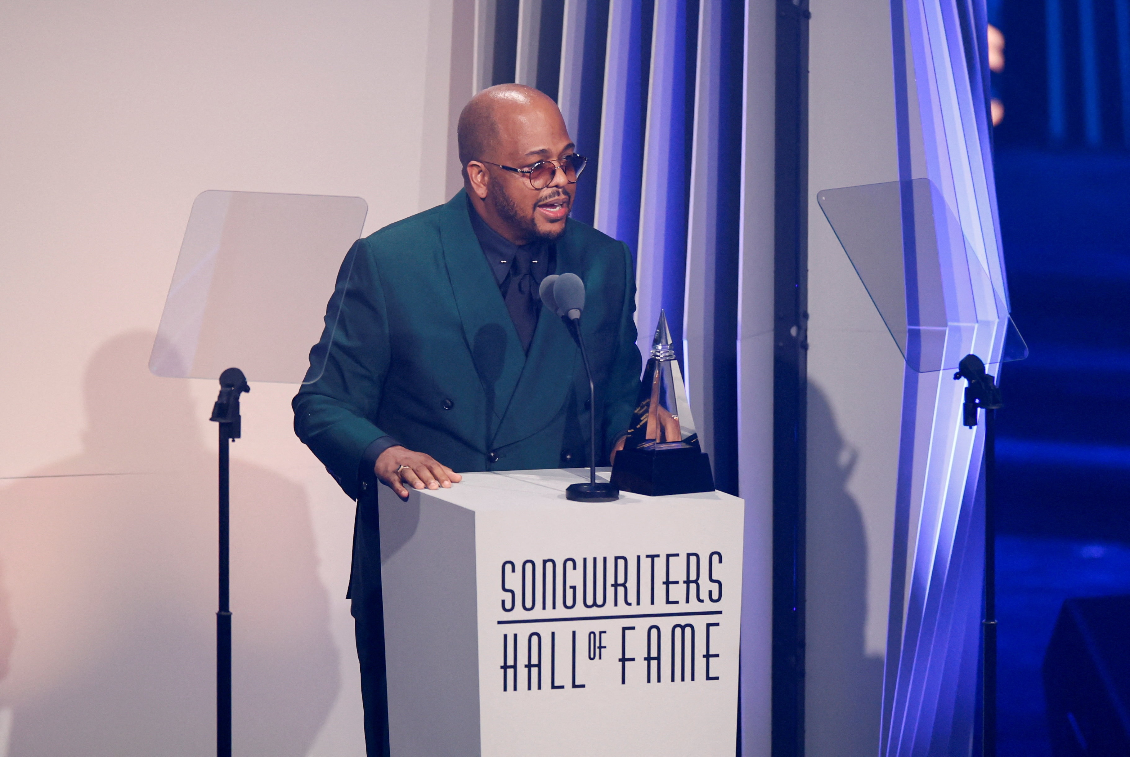 Christopher Tricky Stewart standing at a lectern with an award talking in a microphone