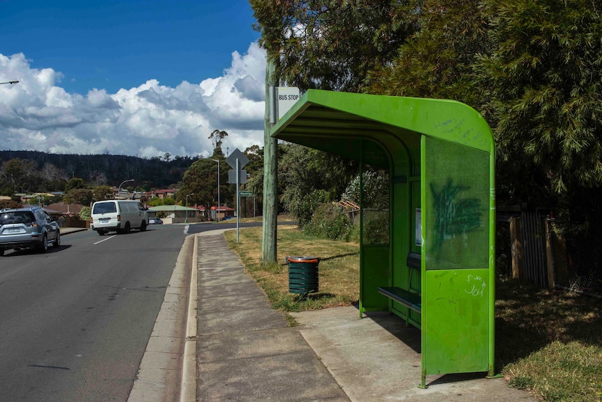 A green bus stop shelter on a suburban street