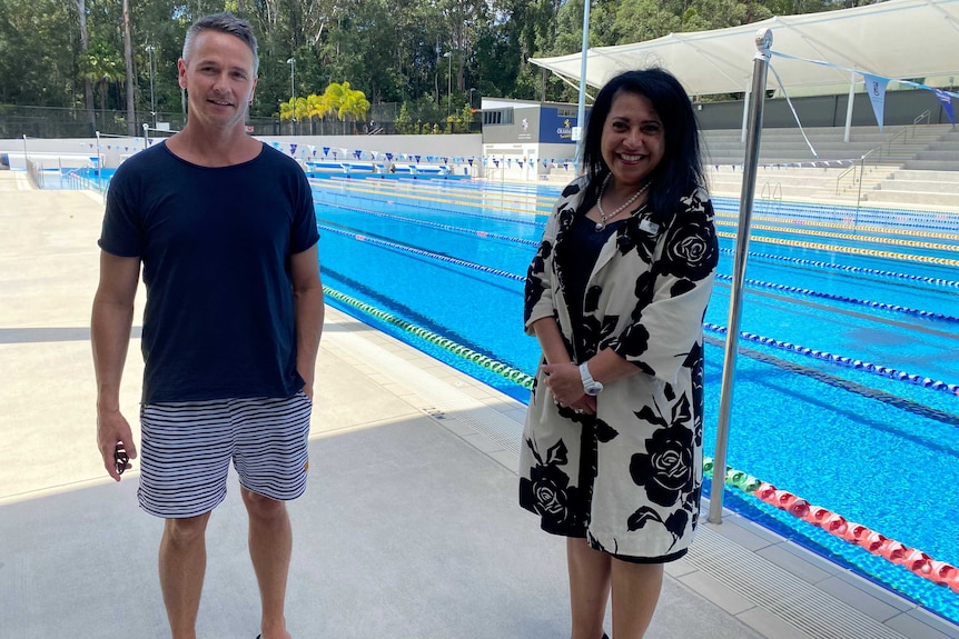 Man and woman stand in front of large pool