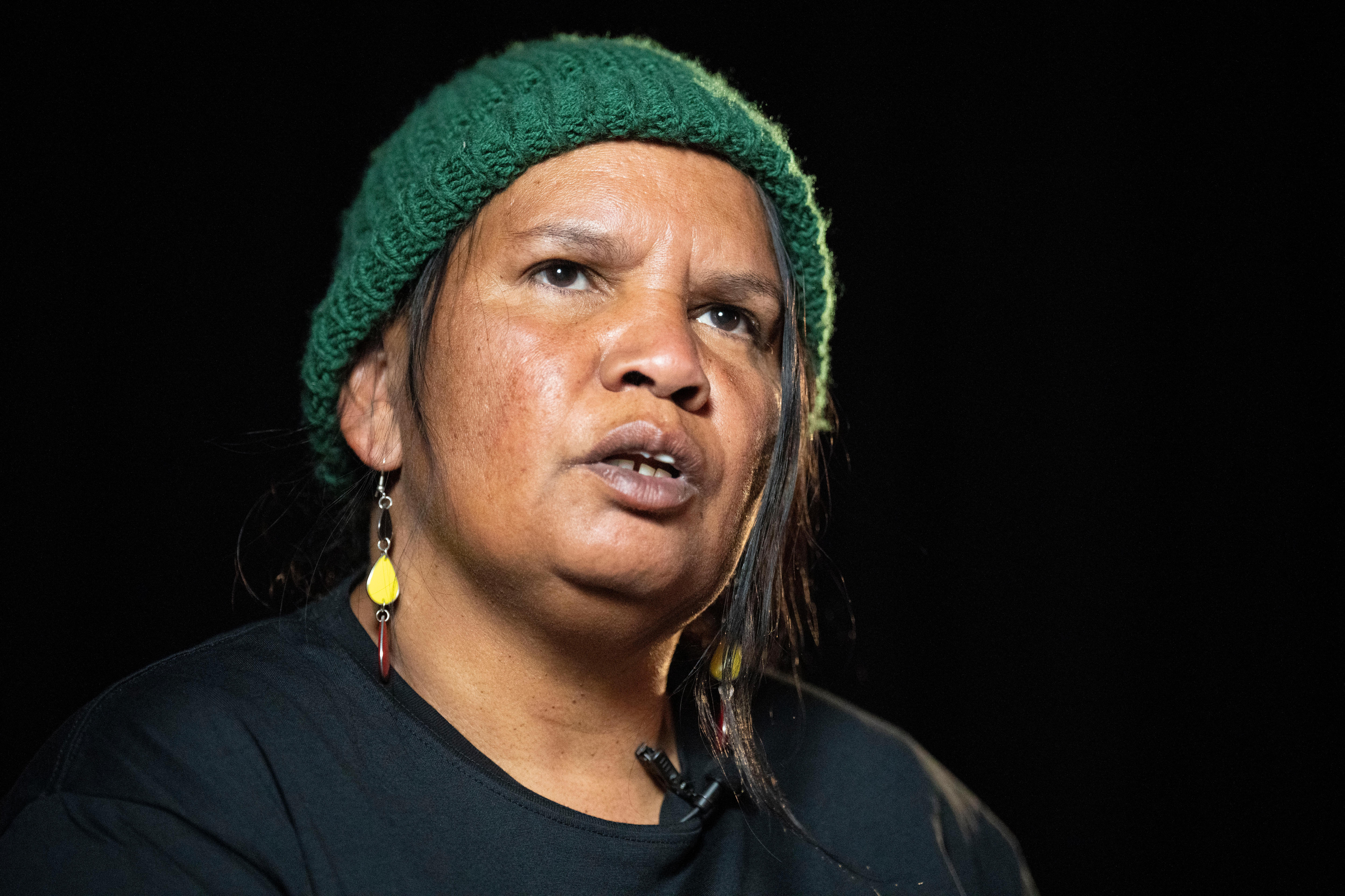 A woman being interviewed in a dark room.