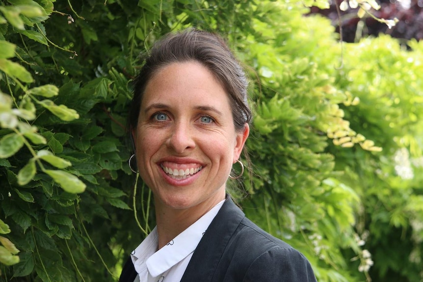 Leanne McLean, Tasmania's children's commissioner, poses for a photo against a background of greenery