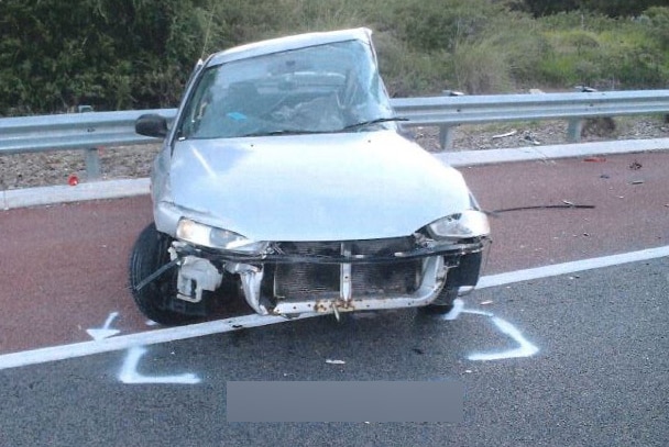 The front of a silver car sitting crashed on the side of the Mitchell Freeway in Perth, with the passenger's side stowed in.