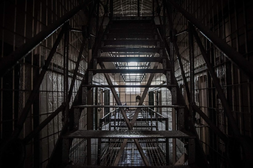 A historic gaol, pictured through an old staircase