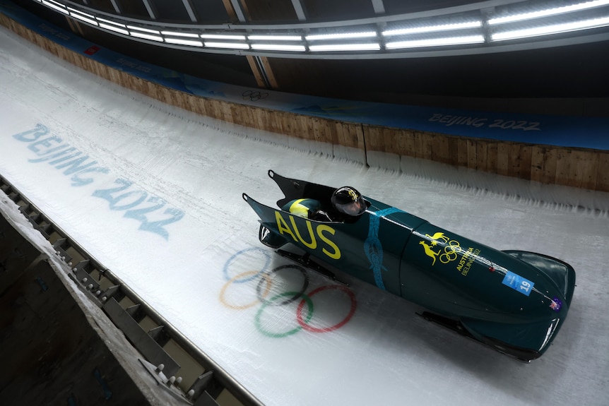 A green bobsleigh drives along an icy track.