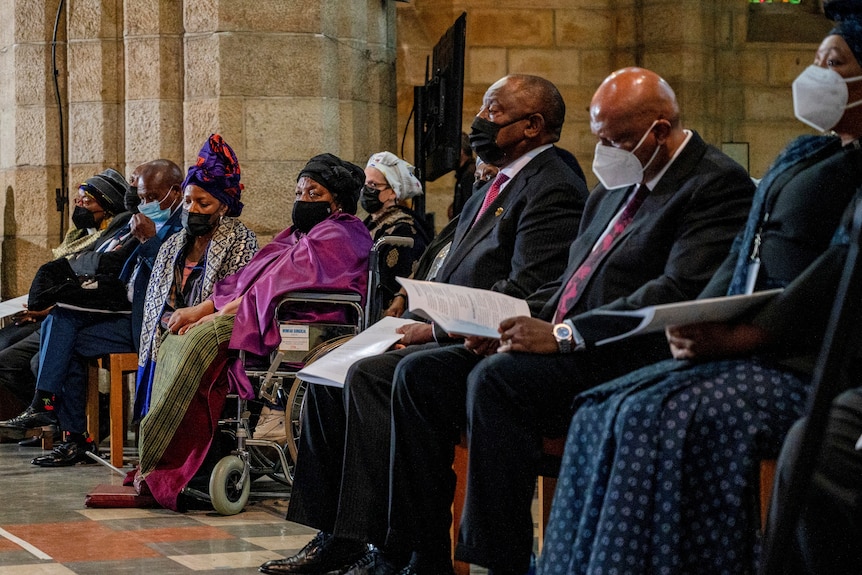 Primera fila de figuras enmascaradas sentadas en una capilla en el funeral de Desmond Tutu