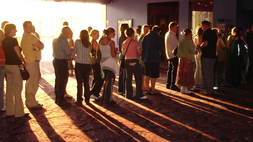 Men and women stand in a line for the bathrooms at a cinema