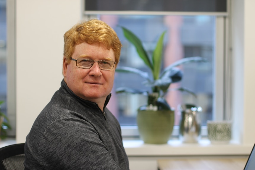 portrait shot of Chris Lund, with plants on windowsill behind him