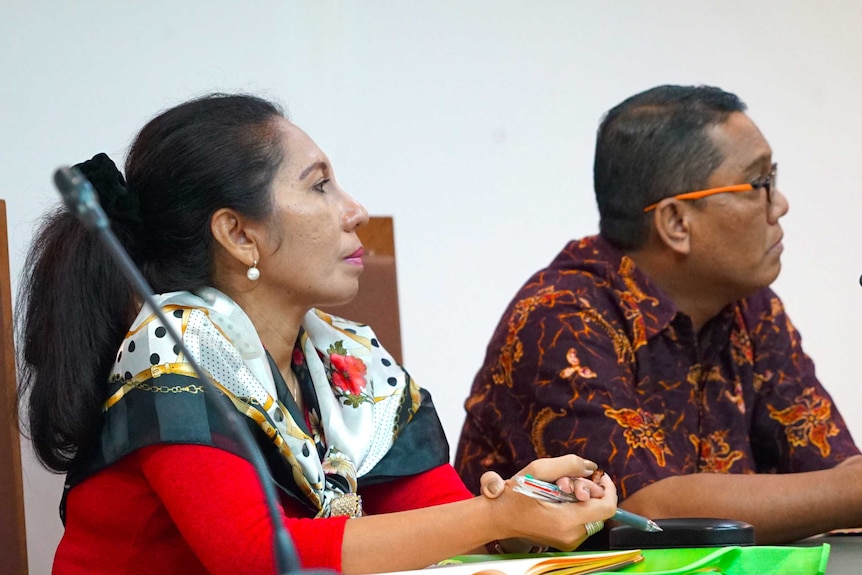 Lawyer Lisa Hiariej sits in an Indonesian court, with her hands together, holding a pen.