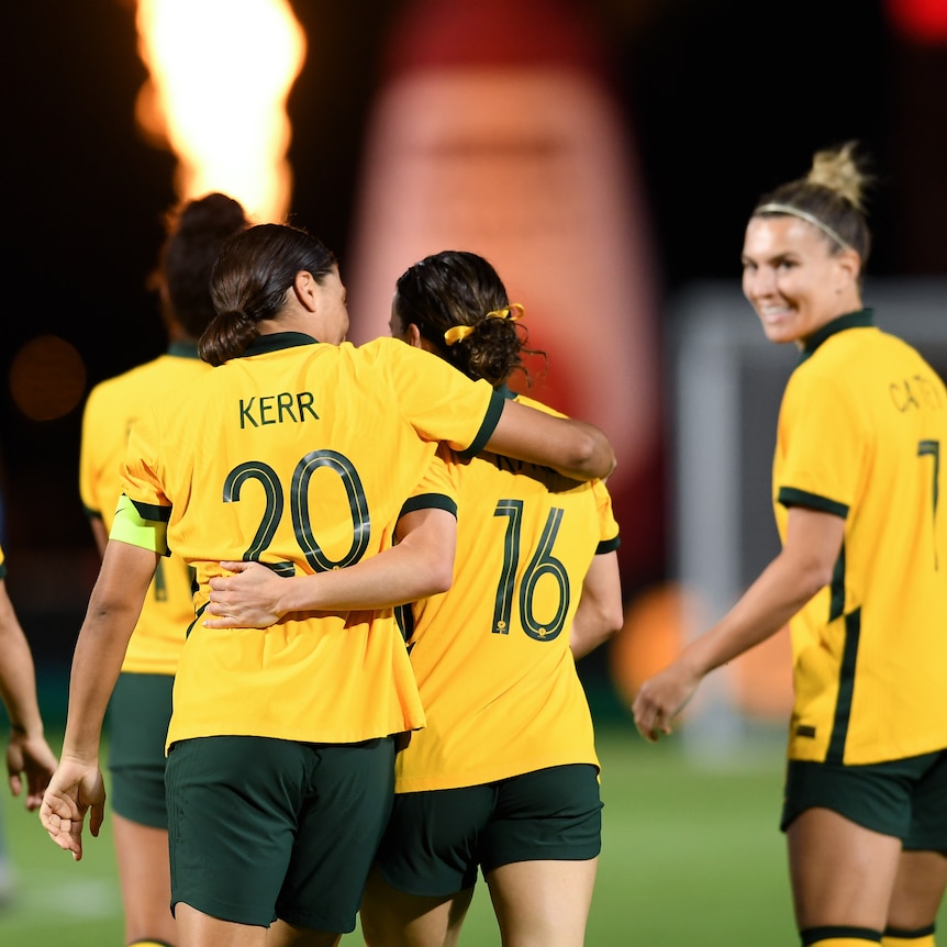 Sam Kerr and Hayley Raso put their arms around each other as they walk away from camera during a Matildas match.
