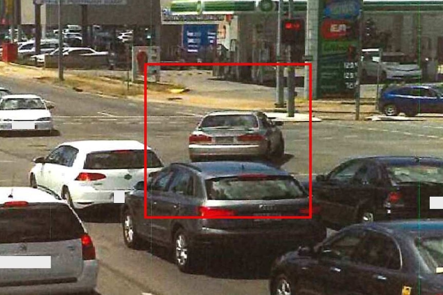 A car with a red square around it going through a red arrow at a major intersection
