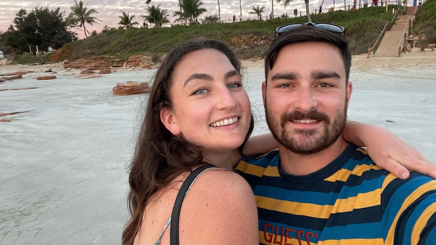 woman and man smiling at camera on cable beach 