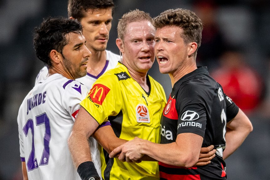 A referee in a yellow shirt gets between Juande and Patrick Ziegler, who both look a bit aggressive