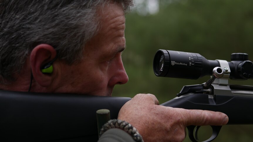 a very close shot of a man looking through the scope of a well-maintained rifle