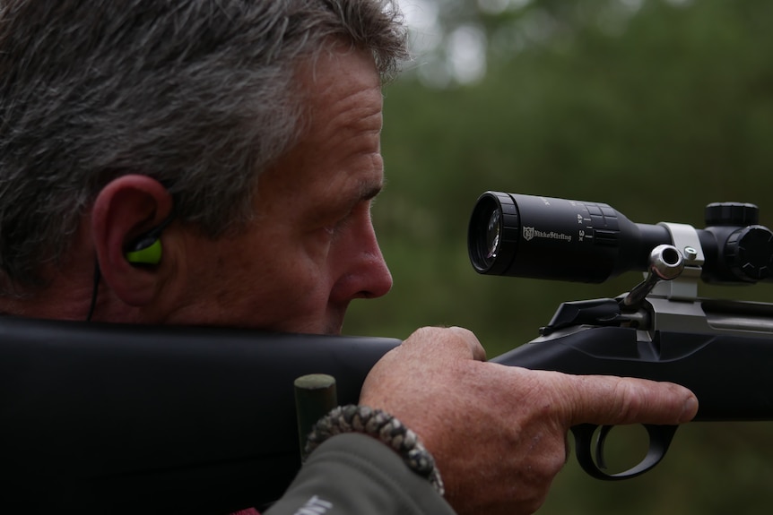 a very close shot of a man looking through the scope of a well-maintained rifle