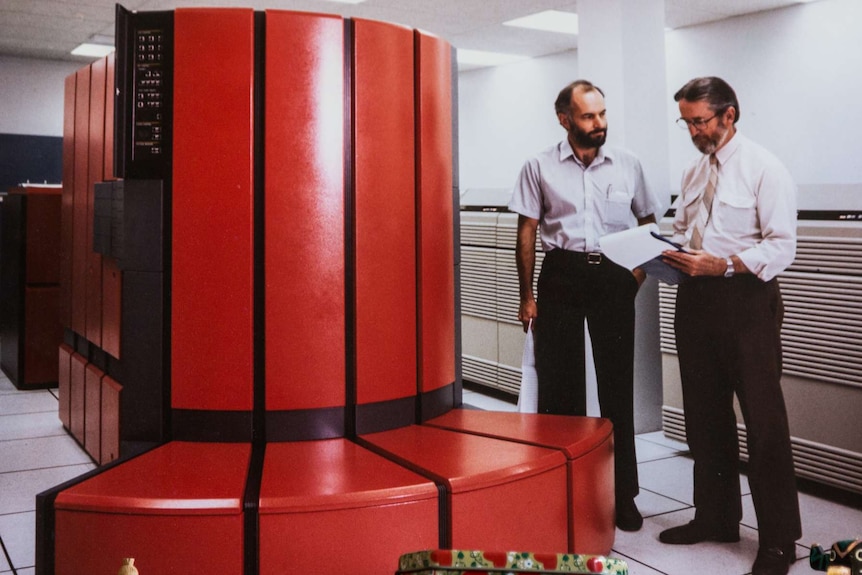 A young Barrie Pittock stands with a colleague in a computer laboratory.