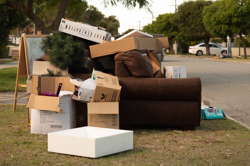 Sofa, cardboard boxes, tree, easel on verge for collection.