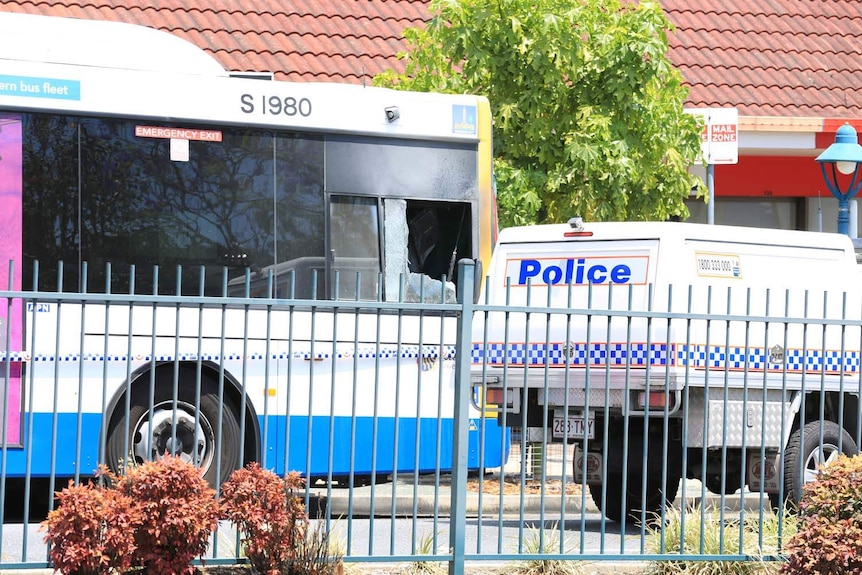 A police vehicle next to a bus with a smashed window.