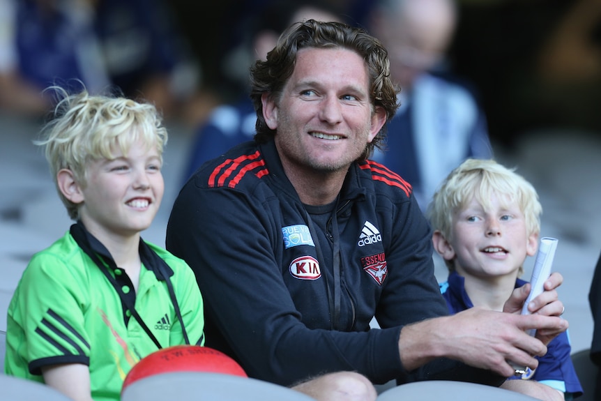 A man sits in between two young boys with blonde hair