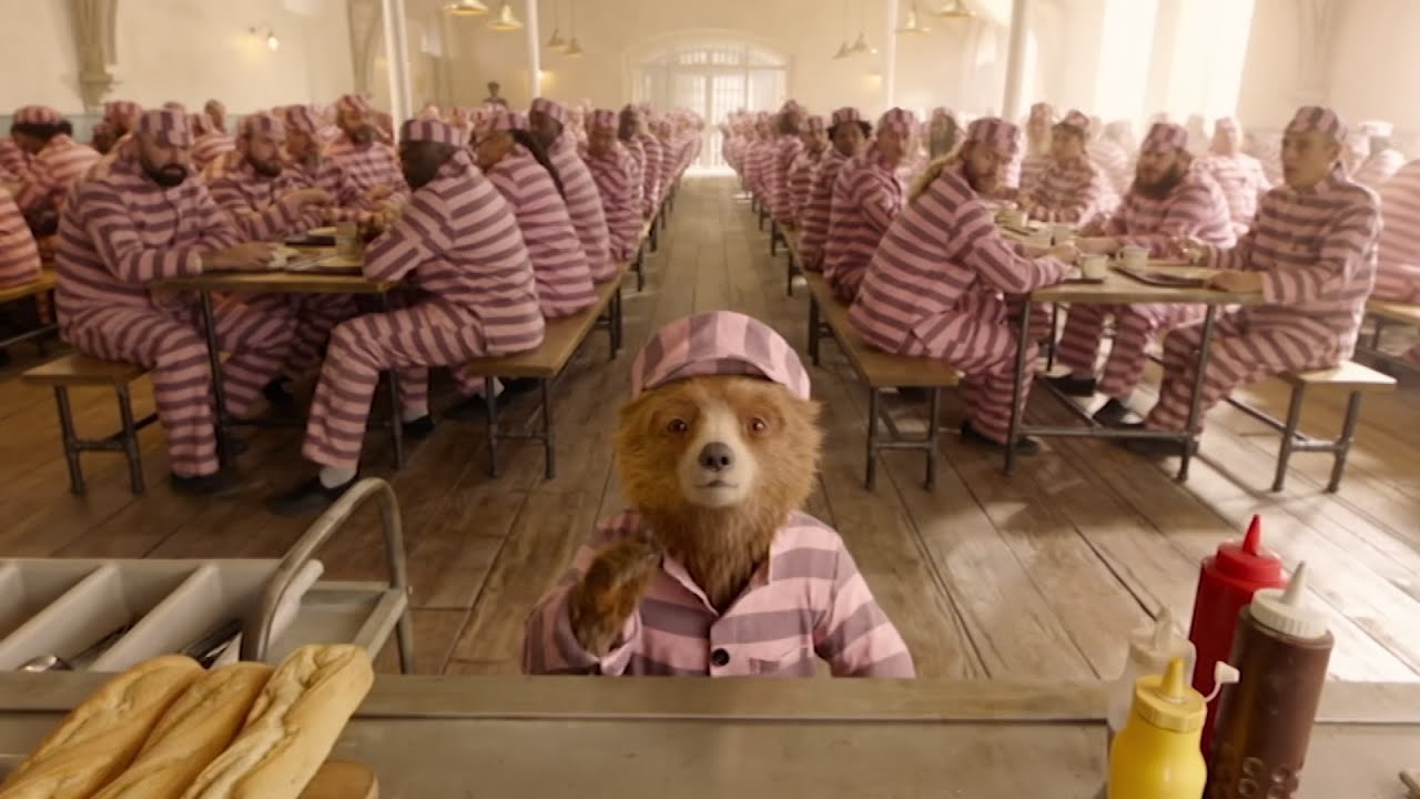 Paddington in a jail mess hall wearing striped clothes.