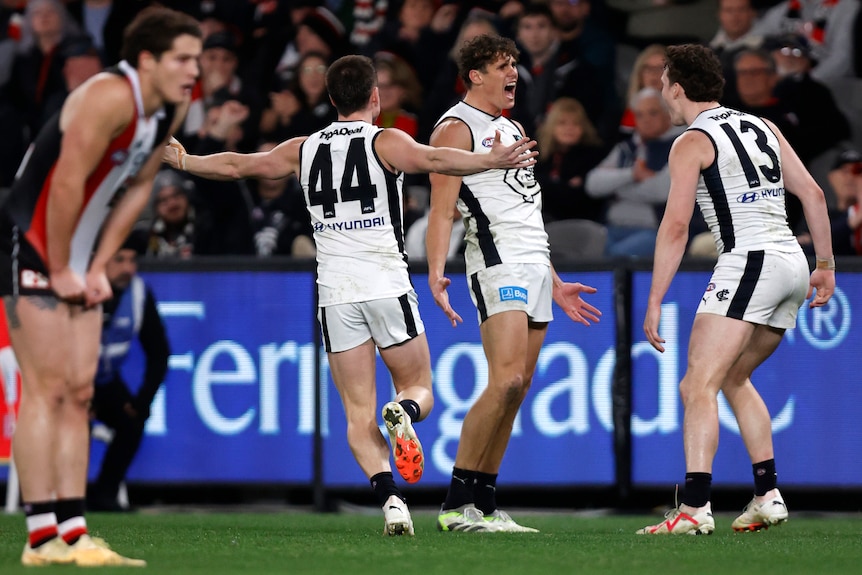 Charlie Curnow yells in delight as teammates mob him