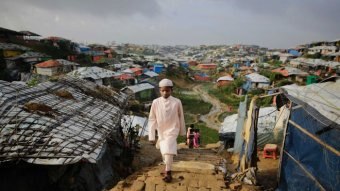 A Rohingya boy walks up a hill through sprawling refugee camps.