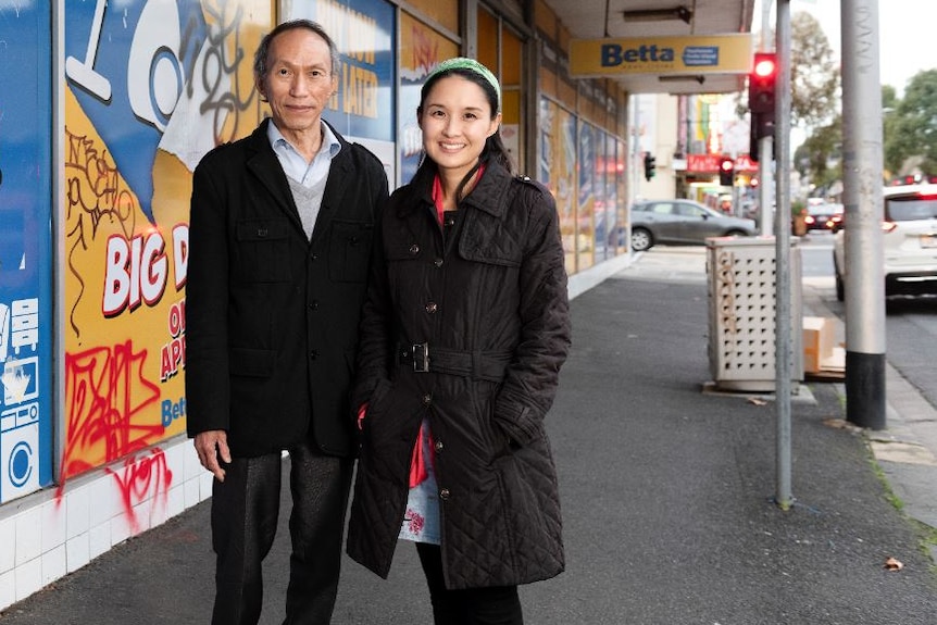 Alice Pung stands smiling to the right of her father, who has thinning dark hair and black jacket, and a slight smile.