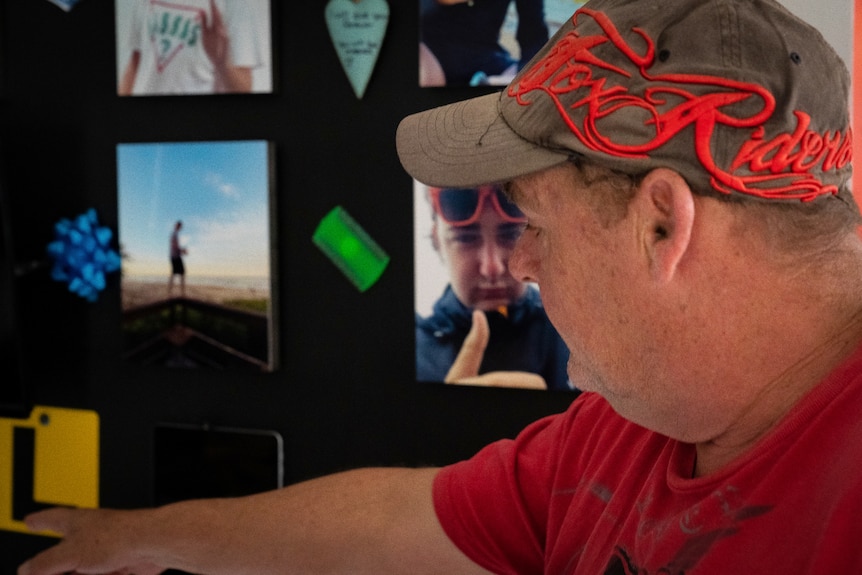 A man points to photos and memorabilia of his late teenage son.
