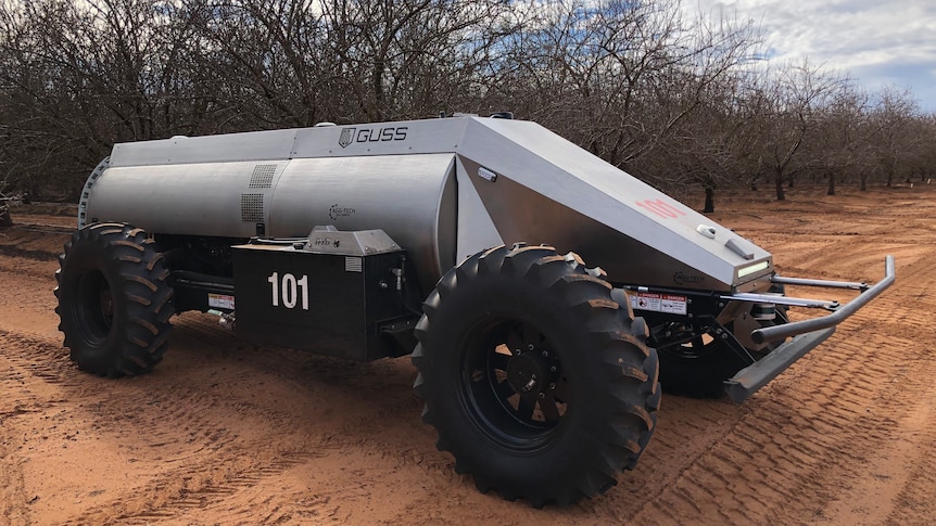 The driverless almond sprayer has a silver body and tractor tyres