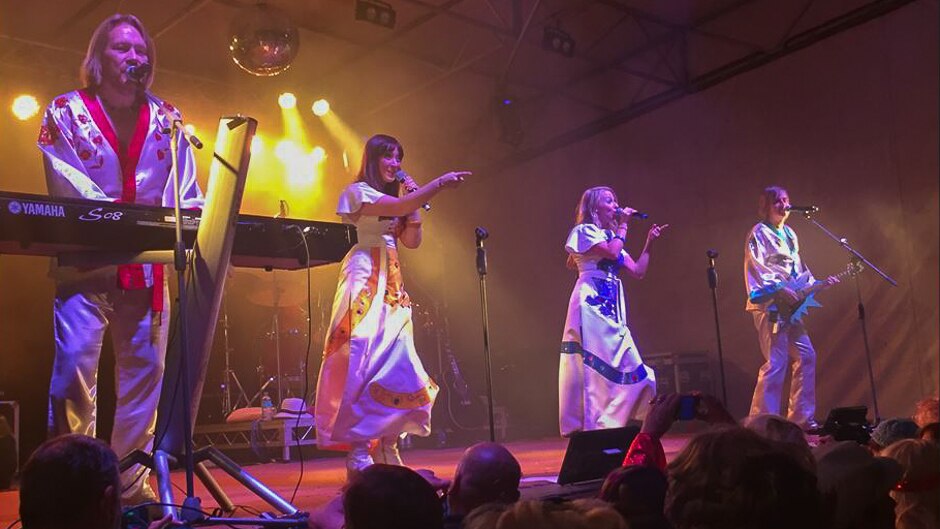 Four ABBA lookalikes perform on stage