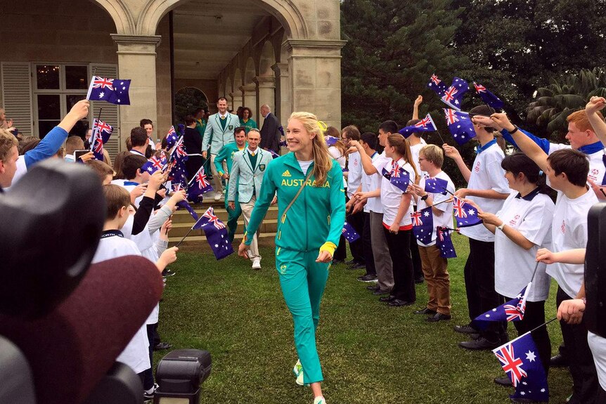 Kim Brennan smiles as people wave flags to welcome the team.
