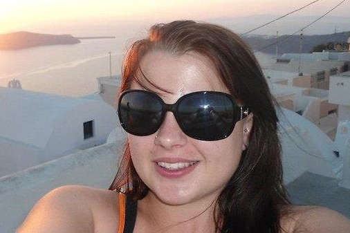 A smiling young woman in dark sunglasses.