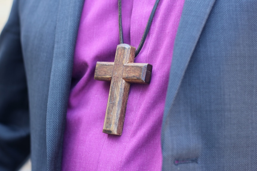A wooden cross worn on a purple shirt 