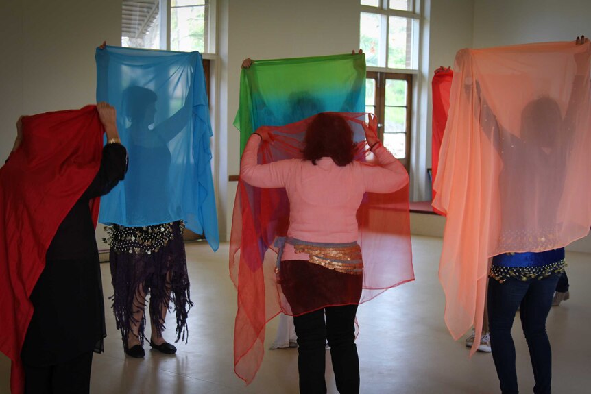Women holding up their scarves during the belly dancing class.