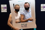 Two men pose for a photo with their arms exposed after receiving a vaccination