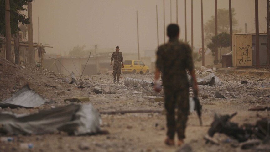 Two soldiers walk towards each other from opposite ends of a debris-covered street