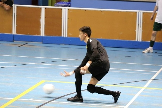 A man in soccer uniform throws a white ball