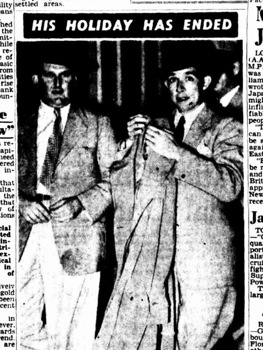 William Dodson holds a coat while looking at the photographer in a black and white newspaper photo. He is dressed in a suit.