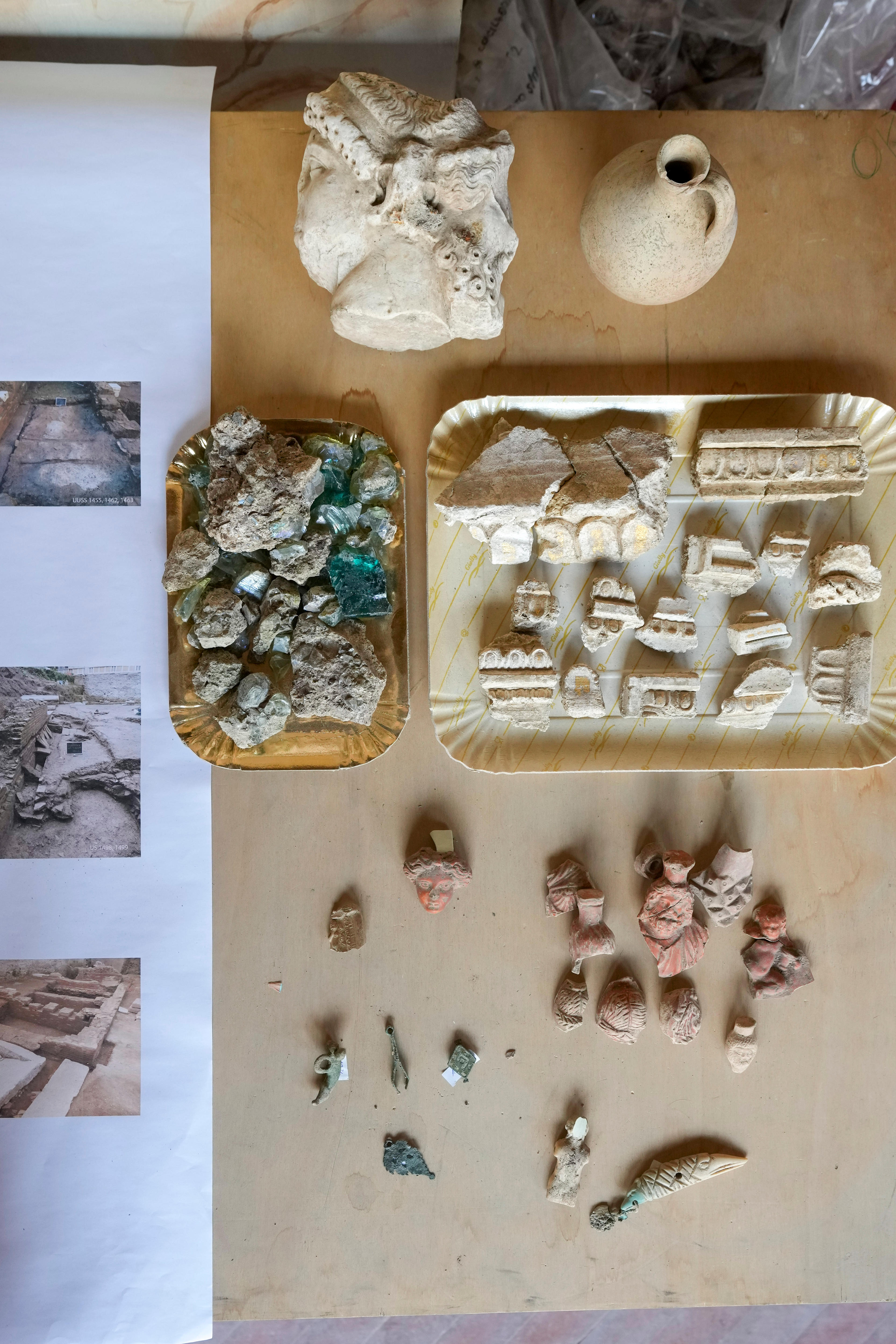 Several tinty pieces of eramic roman ruins and artificacts layed out on a table with one in the shape of a statue head