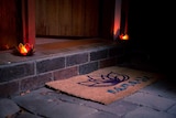 A welcome mat reading Namaste is at an open door, with two candles lit on either side.