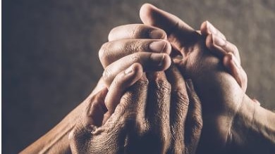 Picture of hands holding each other against a brown background 