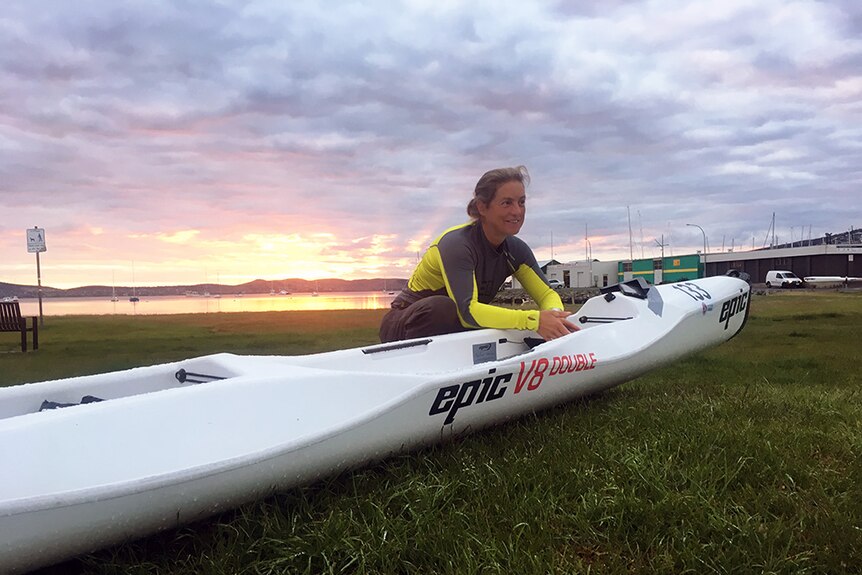 A female paddler prepares a kayak at dawn in Hobart