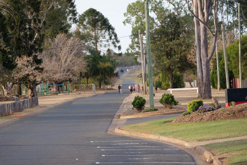 A group of young people walk in the distance in a quiet street.