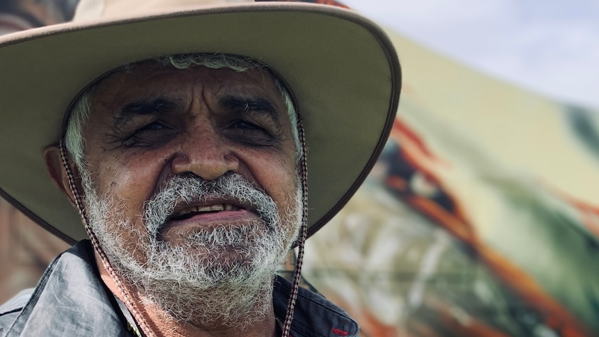 A close-up photo of Uncle Dennis wearing a wide-brimmed hat and looking determined.